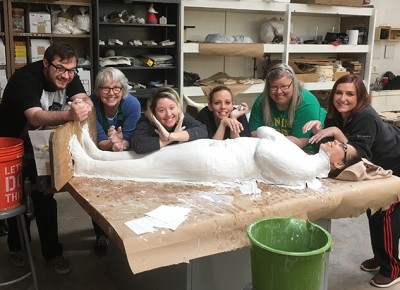 Worcester State University students in the CitySpeak Sculpture class. The plaster over the student lying on the table forms the cast.