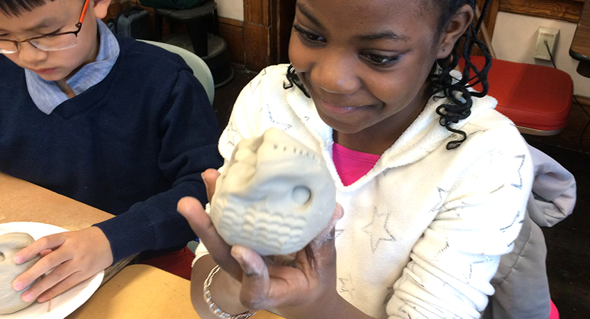 A Worcester elementary school student holds her piece of Native American-style pottery.