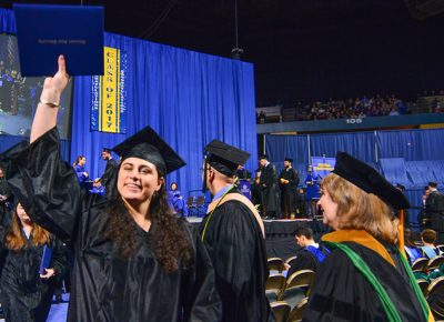 A Worcester State University student holds up her degree at undergraduate commencement.