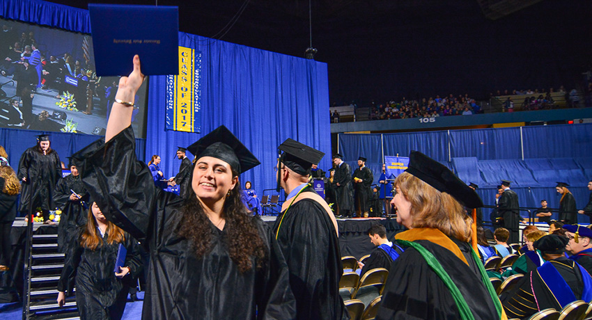 A Worcester State University student holds up her degree at undergraduate commencement.