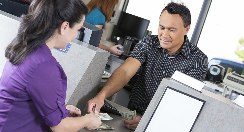 A man gets money from a bank teller.